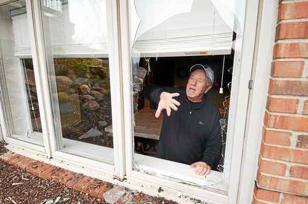 John Osborne shows where two coyotes broke through a window and into his home. (Photo credit: The Macomb Daily)